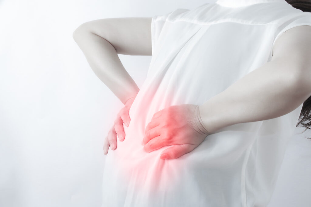 ぎっくり腰で腰に手を当てる人